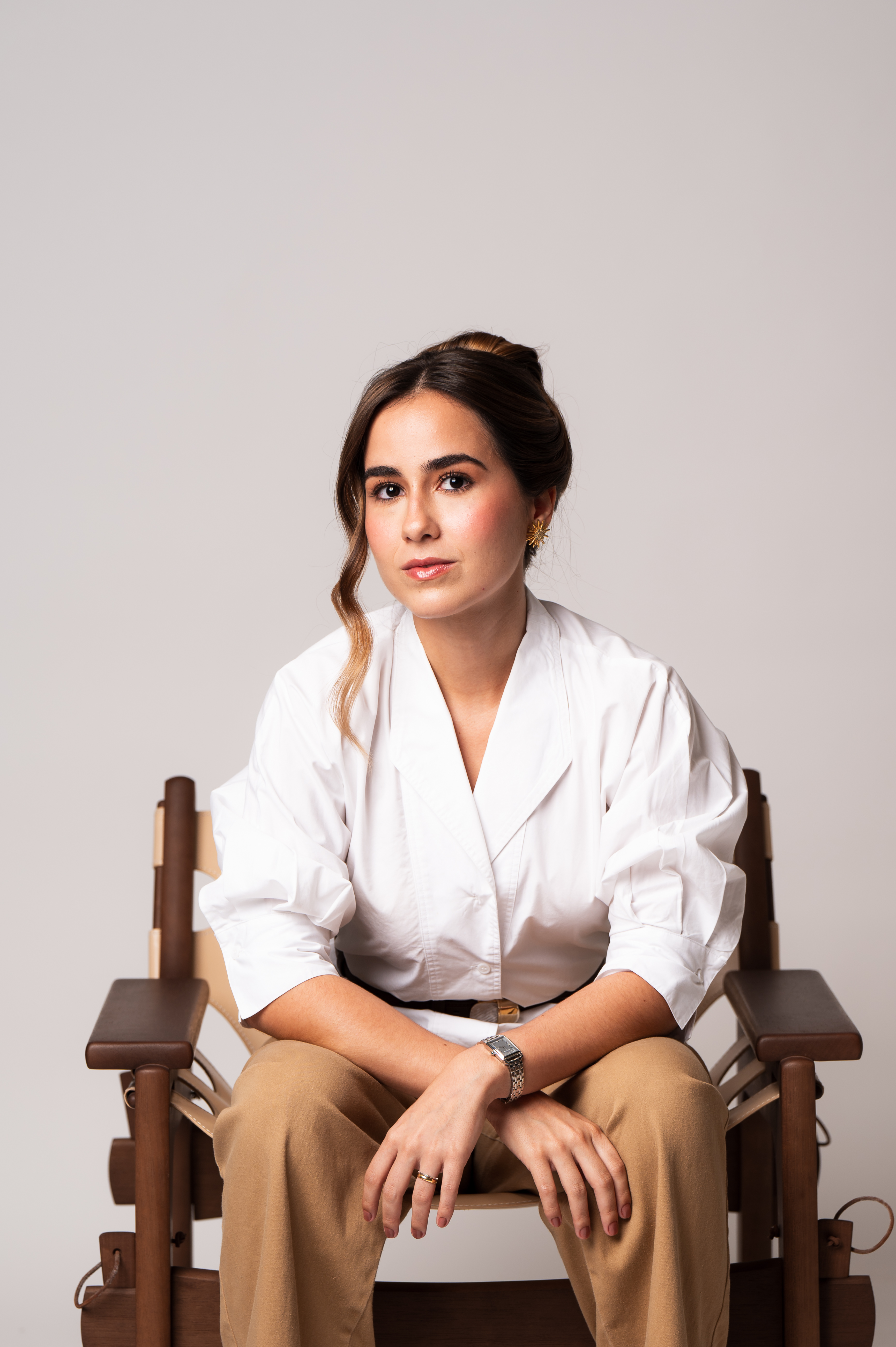 Retrato de Manu Soares sentada em uma cadeira de madeira